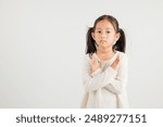 Portrait Asian young kid girl unhappy or confident standing holding two cross arms say no X sign, studio shot isolated white background, Thai kindergarten child pose reject gesture with copy space