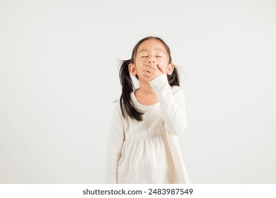 Portrait Asian young kid girl emotions tired and sleepy yawning covering mouth open by hand, studio shot isolated on white background, Thai kindergarten child insomnia concept with copy space - Powered by Shutterstock