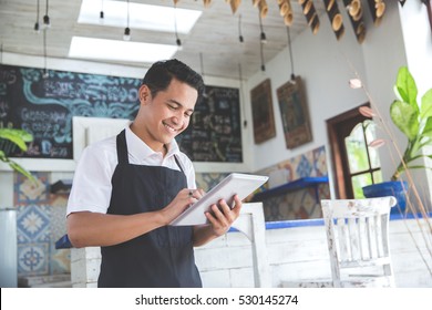portrait of asian young male cafe owner with tablet - Shutterstock ID 530145274