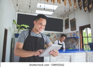portrait of asian young male cafe owner with tablet - Shutterstock ID 538932562