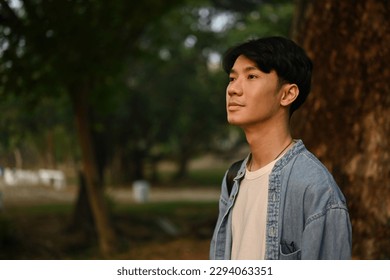 Portrait with Asian young man looking ahead with determined eyes with nature in the background. - Powered by Shutterstock