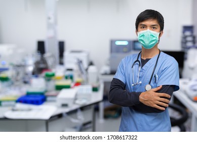 portrait of a Asian young man nurse/Doctor/scientist wearing surgical mask and standing with his arms crossed, Laboratory background