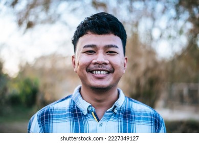 Portrait Asian young man standing with toothy smiling and looking camera, Happily teenager male in plaid shirt with charming smile