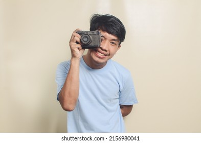 Portrait Of An Asian Young Man Taking A Photo On An Isolated Background