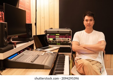 portrait of asian young professional music producer, composer, sound engineer with audio recording equipments in studio