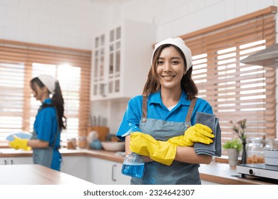 Portrait of Asian young woman arms crossed and smile ready to work cleaning in kitchen room. Housekeeper team in blue uniform apron and put on yellow rubber gloves cleaning service team at home - Powered by Shutterstock