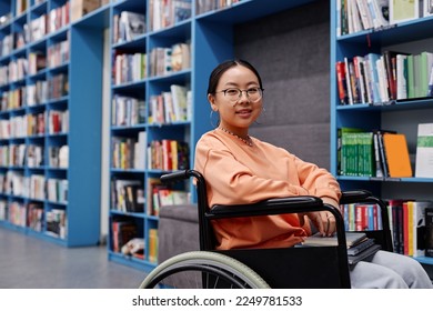 Portrait of Asian young woman with disability in library at modern college smiling cheerfully, copy space - Powered by Shutterstock