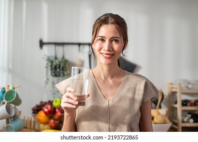 Portrait of Asian young woman drink a glass of milk in kitchen at home. Attractive female looking at the window, holding and sipping a cup of milk after wake up in the morning for health care at house - Powered by Shutterstock