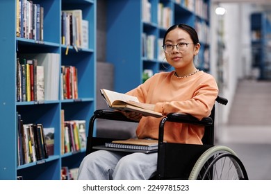 Portrait of Asian young woman in library setting at modern college smiling at camera - Powered by Shutterstock