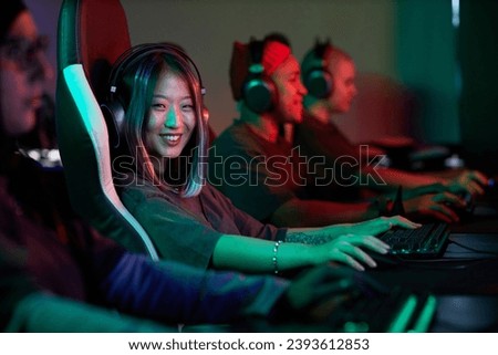 Portrait of Asian young woman playing video games and smiling at camera in pro cybersports team, copy space