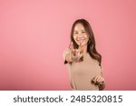 Portrait of Asian young woman showing I LOVE YOU gesture in sign language in studio shot isolated on pink background, Hand sign language, Valentine Day