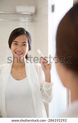 A portrait of an asian young woman will brushing her teeth happily