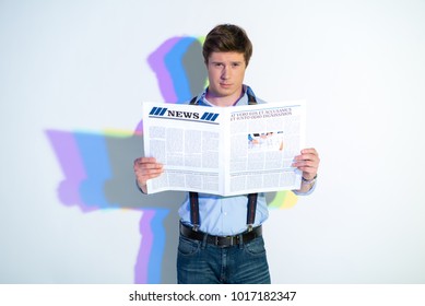 Portrait of assertive man looking through newspaper. Painted reflection reflecting on wall. Press concept