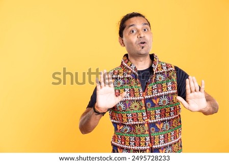 Portrait of assertive man trying to stop misunderstanding using calming hand gesture to diffuse tensions, doing peaceful resolution. Indian person doing calm down sign gesturing, isolated over studio