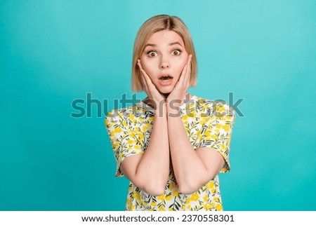Portrait of astonished girl with short hair wear colorful t-shirt hold palms on cheekbones staring isolated on turquoise color background