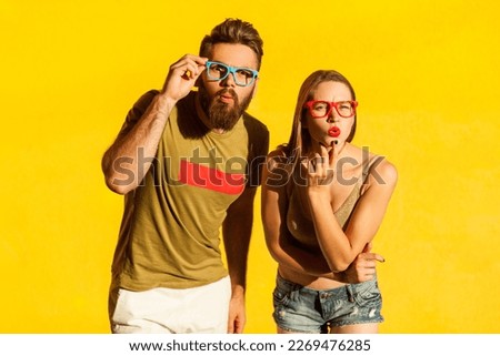 Portrait of astonished surprised man and woman looking at camera with big eyes and shocked facial expression, sees something amazing. Indoor studio shot isolated on yellow background.