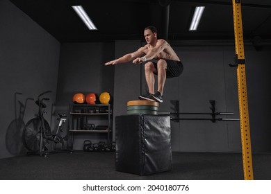 Portrait of an athletic man doing box jump exercise. Crossfit, sport and healthy lifestyle concept. Shot of a young man train jumping onto box as part of exercise routine. Cross, functional training - Shutterstock ID 2040180776