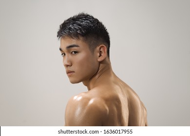Portrait Of Athletic Muscular Asian Man Standing On A Grey Background. Attractive Confident Young Man Looking Away. Male Fashion Shot, Muscular Asian Guy