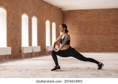 Portrait Of Athletic Young Lady Exercising Outdoors In Empty Urban Building, Motivated Millennial Woman Stretching Leg Muscles, Warming Up Before Jogging Outdoors, Enjoying Outside Trainings