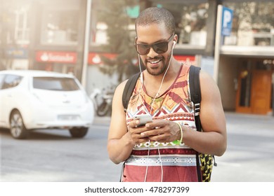 Portrait of attractive African athlete in sunglasses coming home after workout at fitness club, messaging via social networks and using earphones for listening to music. Healthy lifestyle concept - Powered by Shutterstock