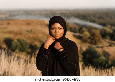 Portrait of attractive african girl in black traditional robe. Salah praying in god