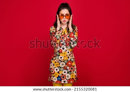 Portrait of attractive amazed funny cheerful girly girl touching specs pout lips isolated over bright red color background