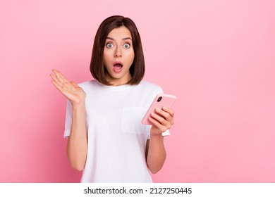 Portrait of attractive amazed stunned girl using device chatting copy space wow omg post isolated over pink pastel color background