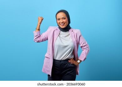 Portrait of attractive Asian woman demonstrates strong hand over blue background