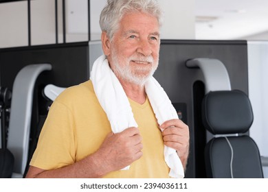 Portrait of attractive bearded senior man after exercises in gym. Smiling mature man wipes sweat satisfied with his workout. Sport, gym, wellness concept - Powered by Shutterstock