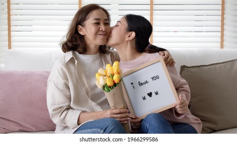 Portrait Attractive Beautiful Mum Sit With Daughter Give Gift Photo Frame And Flower In Family Moment Celebrate Look At Camera. Overjoy Bonding Cheerful Kid Embrace Relationship With Retired Mom.