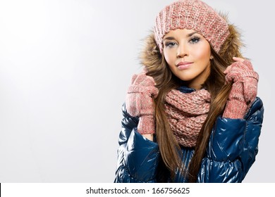 Portrait of attractive beautiful young woman wearing gloves, scarf and winter cap, white background