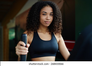 Portrait Of Attractive Black Woman With Afro Hair Using A Treadmill At Gym Looking To The Camera