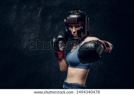 Portrait of attractive boxer in protective helmet and gloves ready to fight.