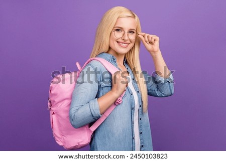 Portrait of attractive brainy cheerful girl touching specs going back to school isolated over bright violet purple color background