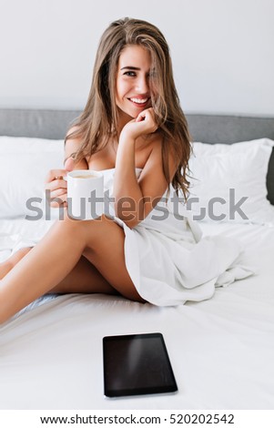 Portrait Attractive Brunette Girl With Naughty Legs On White Bed In Modern Apartment She Holds Portrait Attractive Brunette Girl With Naughty Legs On White Bed In Modern Apartment She Holds