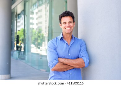 Portrait of an attractive business man smiling with arms crossed in the city