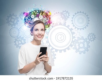 Portrait of Attractive business woman in formal wear standing in front of light blue wall with colorful brain sketch, holding a smart phone and wondering about business improvement measures.