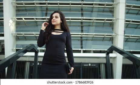 Portrait Attractive Businesswoman Entrepreneur Walking Downstairs In Slow Motion At Street. Sexy Woman Touching Hair In Stylish Dress Outside. Happy Business Woman Smiling On Stairs Outdoors.