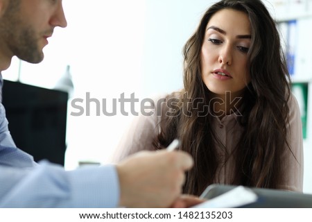 Portrait of attractive businesswoman looking at important business paper. Smart man in blue shirt holding contract. Biz meeting concept. Blurred background