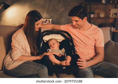 Portrait Of Attractive Careful Couple Rocking Baby In Chair Spending Time Sitting On Divan Late Sleepless Night At Home Indoors