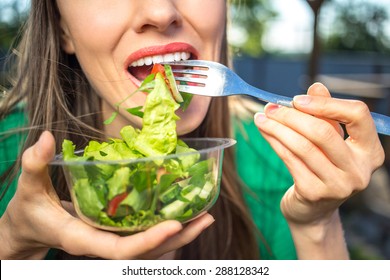 Portrait of attractive caucasian smiling woman eating salad,  focus on hand and fork - Shutterstock ID 288128342