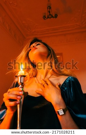 Portrait of attractive caucasian woman with candlestick in the dark, vintage elegant interior.