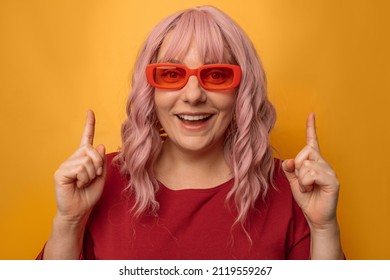 Portrait of attractive caucasian woman raises finger up, showing copy space, spreading information isolated on pink background - Shutterstock ID 2119559267
