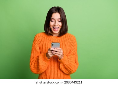 Retrato de atractiva alegre chica asombrada usando el dispositivo gadget app smm aislado sobre fondo de color verde brillante