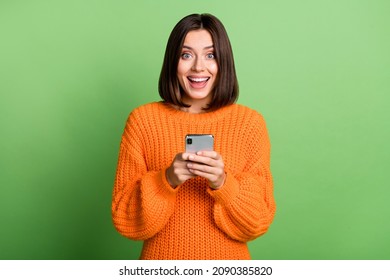 Portrait of attractive cheerful amazed girl using gadget social network post isolated over bright green color background Arkistovalokuva
