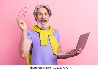 Portrait of attractive cheerful amazed skilled gray-haired man using laptop having fun isolated on pink pastel color background - Shutterstock ID 1932307172