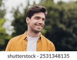 Portrait of attractive cheerful brown-haired guy traveling abroad spending time in garden outdoors