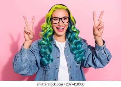 Portrait of attractive cheerful carefree wavy-haired girl showing double v-sign isolated over pink pastel color background