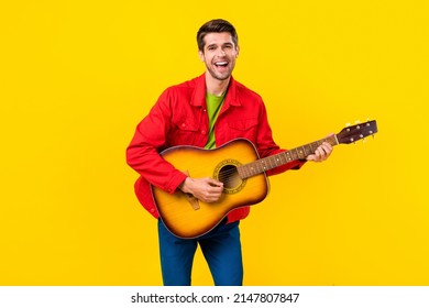 Portrait Of Attractive Cheerful Cool Guy Playing Guitar Having Fun Singing Isolated Over Bright Yellow Color Background