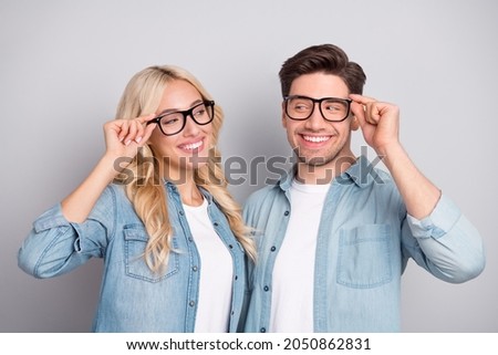 Portrait of attractive cheerful couple touching specs good mood isolated over grey pastel color background